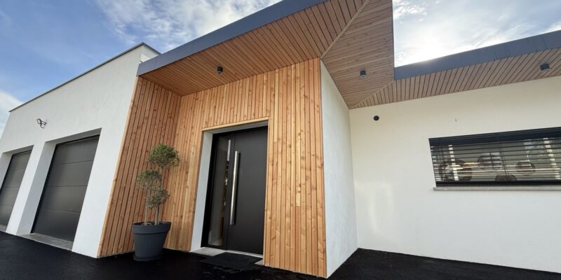 Extérieur contemporain de la maison avec une porte d’entrée noire en panneaux de bois verticaux.